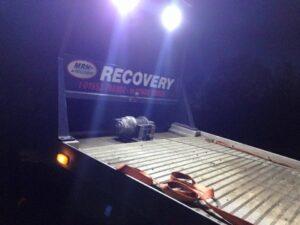 Recovery vehicle at night with lights on
